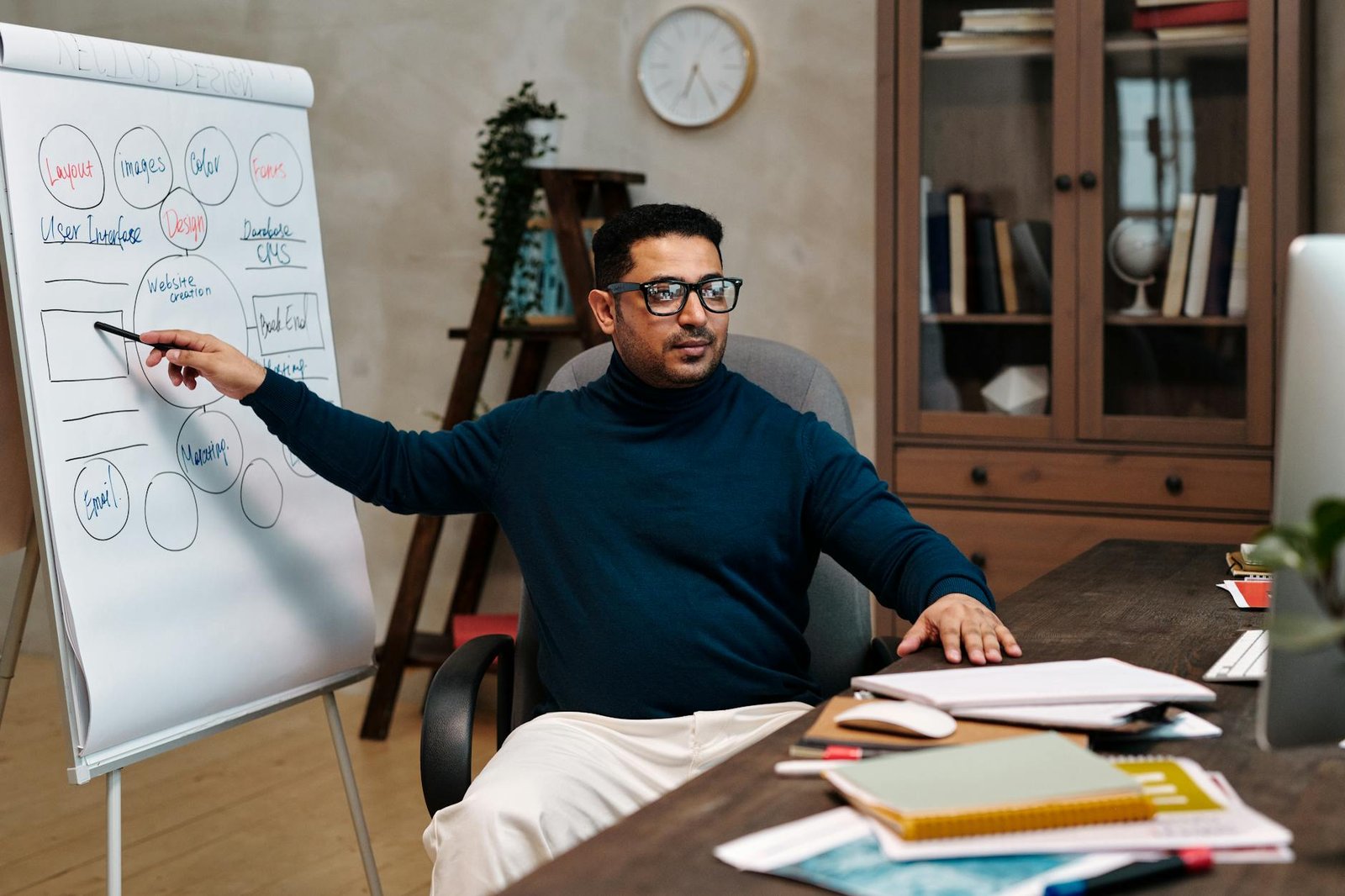 man in long sleeve pointing while sitting on an office chair